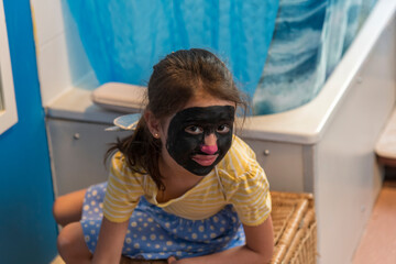 A young girl from poor deprived family is entertaining herself by face painting