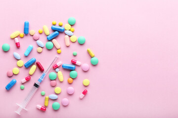 Colorful pills with syringe on pink background