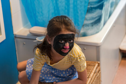 A young girl from poor deprived family is entertaining herself by face painting