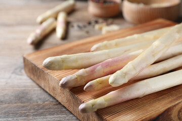 Fresh white asparagus and cutting board on wooden table, closeup