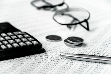 Row of coins,pen,glasses, calculator and finance reports on the table for finance and banking concept. Business accounting