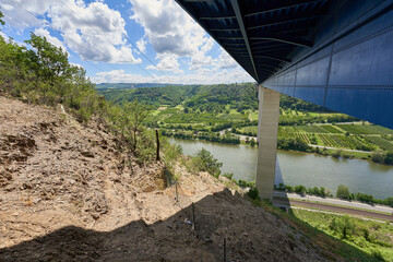 Mosel valley bridge from below, blue steel construction is supported by large gray pillars, blue...