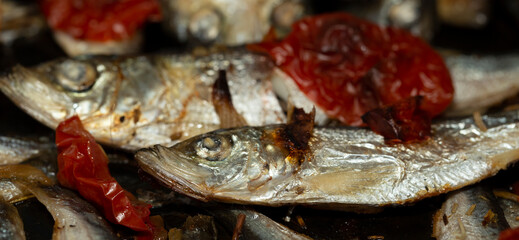 Baltic herring baked in a baking tray with tomatoes and onions.