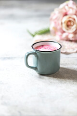 Ayurvedic rose moon milk. A trendy relaxing form of drink before bed. Milk with rose petals in a gray mug on a light concrete background.