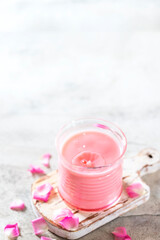 Ayurvedic rose moon milk with a little splash in the glass. A trendy relaxing form of drink before bed. Milk with rose petals on a light concrete background.