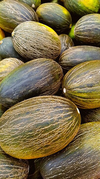 Santa Claus melon or piel de sapo (toadskin) group in the market with texture close up for a vertical background wallpaper