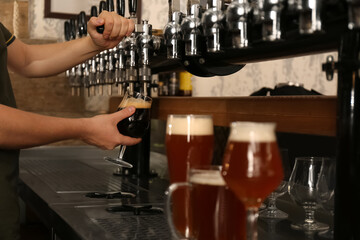 Fototapeta na wymiar Bartender pouring fresh beer into glass in pub, closeup