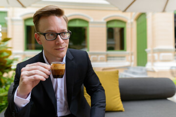 Young handsome blond businessman drinking coffee and thinking at the coffee shop