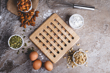 Healthy baking ingredients - flour, almond nuts,  eggs, over a stone table background. Bakery background frame. Top view, copy space.