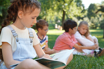 Cropped shot of a lovely young girl reading a book outdoors at the park on a warm summer day
