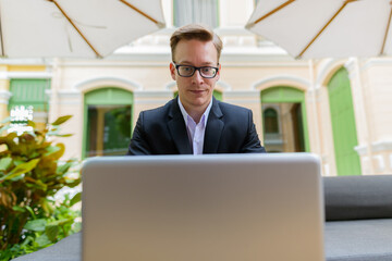 Young handsome blond businessman using laptop at the coffee shop