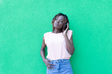 beautiful African American in headphones dancing, against a green background