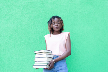 beautiful African American with a book on a green background, a student