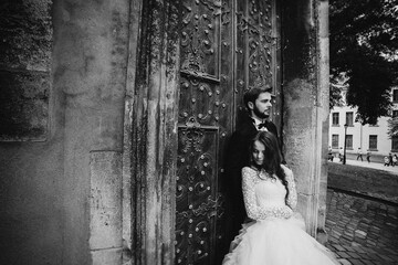 black and white photo. Wedding couple hugs near the vintage green door. Stone walls in ancient town...