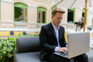 Young handsome blond businessman using laptop at the coffee shop