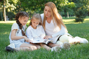 Fototapeta premium Two little girls enjoying open air lesson in the park with their favorite teacher