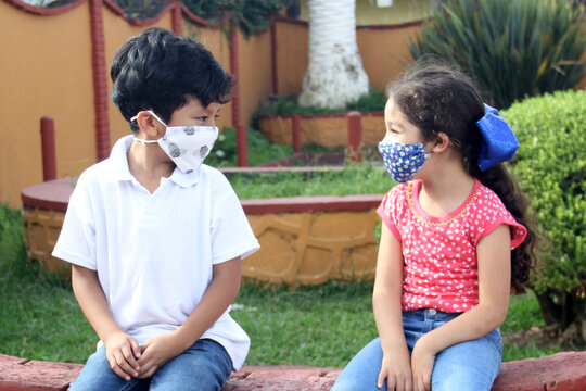 6-year-old Latino Boys Couple With Face Masks Sitting Waiting To Play In Times Of Covid-19