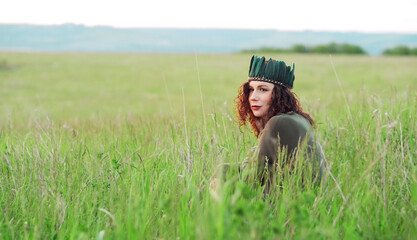 Close-up portrait of a young woman of 25-30 years old with curly red hair, in a green dress and a...