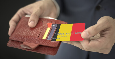 Obraz premium Businessman pulls credit card with flag of Belgium out of his wallet, fictional card number