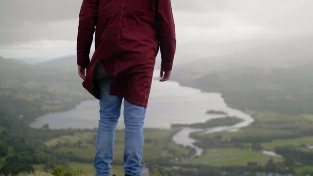 Young Man Turning to look the Fantastic Landscape with Mountain Range and Lake in Scotland