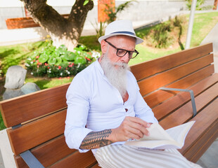 Hipster senior sitting on a bench and read a book - Leisure activities - Elegant elderly man enjoy...