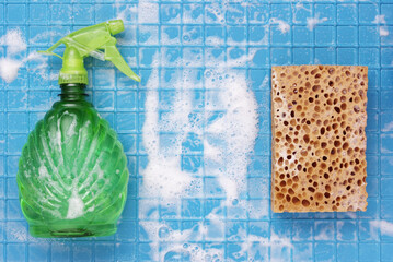 Cleaning tool sprayer and sponge with white foam on a blue wall with cages