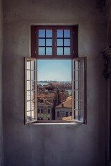 Vertical shot of an opened window with a beautiful view of Venice's cityscape © Evi Radauscher/Wirestock