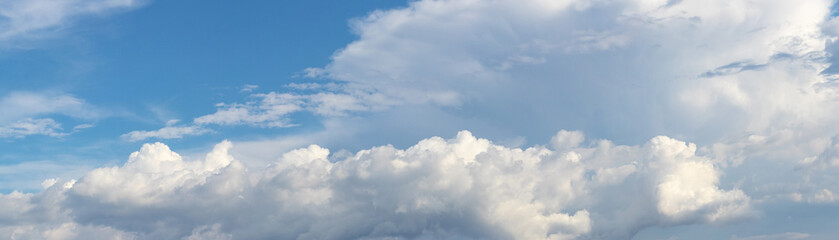 Panorama of blue sky with white curly clouds