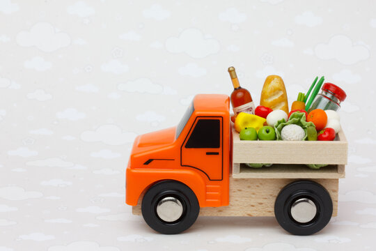 An orange  toy truck delivering food and drinks in a wooden box. Food supply  and food donation concept.