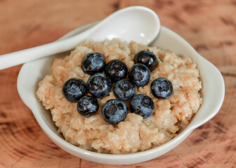 Oatmeal with blueberries. Healthy breakfast. Wooden background. Top view. Selective soft focus. Shallow depth of field.