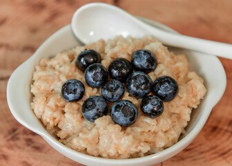 Oatmeal with blueberries. Healthy breakfast. Wooden background. Top view. Selective soft focus. Shallow depth of field.