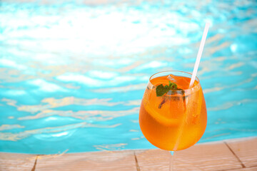 Glass of delicious cocktail near swimming pool, space for text. Refreshing drink