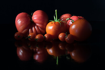 Tomatoes on a black surface and black background.