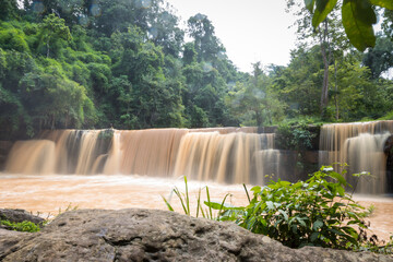 Obraz premium Flash flood in Waterfall . Waterfall from flash flood in the rain forest. flash flood cascading down the brown waterfall from the tropical rain forest.