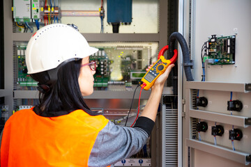 Young female maintenance engineer testing voltage with digital multimeter