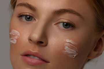 Closeup happy young woman applying cream to her face Skin care and cosmetics concept. Cosmetics. Woman face skin care.Natural makeup, touching face.