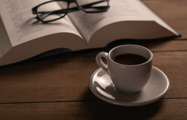 Cup of coffee and a book on a wooden table