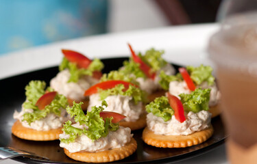 Closeup Tuna salad with crackers on black dish. Canape Tuna. Selective focus and blurred background.