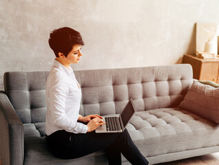 Young girl serfing web using her laptop sitting on the sofa