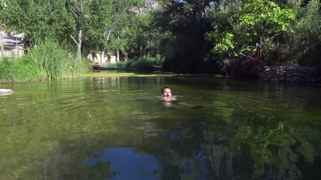 Swimming in the river on hot summer days. Summer outdoor activities. Man is bathing in the river in a wild place.