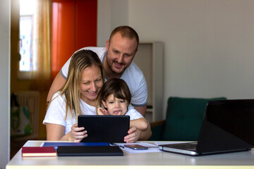 Fototapeta na wymiar Caucasian family with son using laptop at home,shopping online,watching video or movie,smiling mother and father spending weekend together with child,sitting on sofa.Portrait of family watching movie