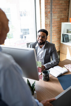 Smiling Businessmen Talking At Computer In Office