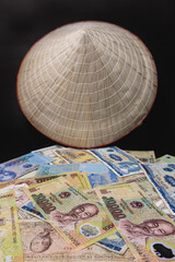 Vietnamese currency and hat. Black background.
