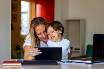 Happy laughing single mother and little preschool cute son using laptop online application,making video call,having fun,babysitter teaching small boy use computer,watching cartoons together.Copy space