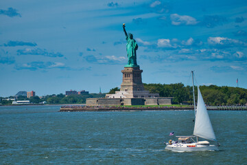 yacht in front of the statue of liberty on a sunny summer day © Alexey