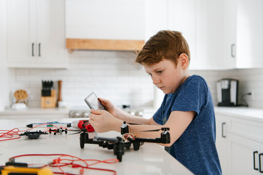 Boy with digital tablet learning to assemble drone at kitchen counter