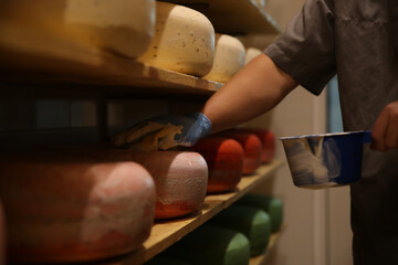 Worker coating cheese with wax in factory warehouse, closeup