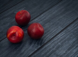 Red fresh plums on a dark background. Space for text