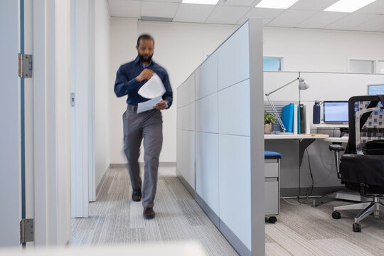 Mature man walking with documents in office