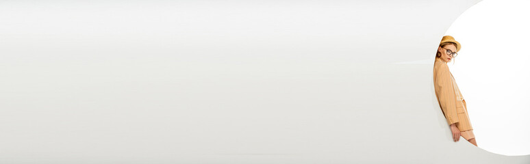 Panoramic shot of stylish woman looking at camera near circle on white background